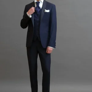 Smoking rever a scialle in sablè di lana blu abbinato 
a Gilet monopetto in seta damascato blu navy